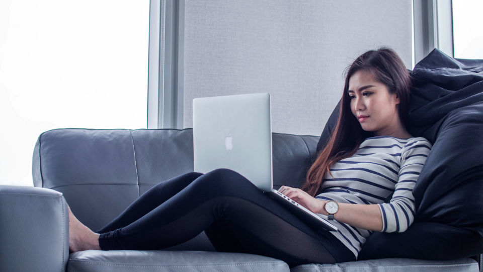 Woman reclining on sofa using laptop